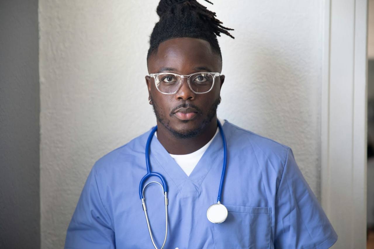 A healthcare professional in blue scrubs with a stethoscope around his neck